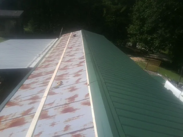 Old rusted panels beside newly installed green metal roofing — Wind Damage Roof Repair by Roofing Brothers in Fruitland Park