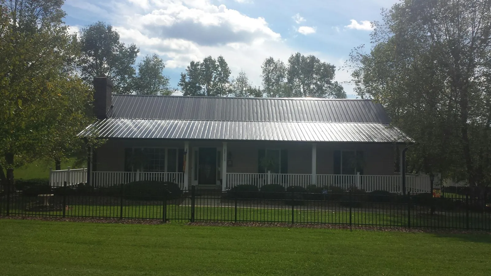 Gray metal roof on a brick ranch with a full width front porch — Gutter Guard Installation work by our crew in Fruitland Park