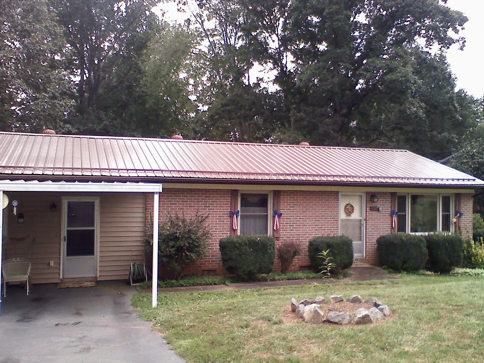Bronze metal roof and carport on a brick ranch home — Roof Repair work by our crew in Fruitland Park