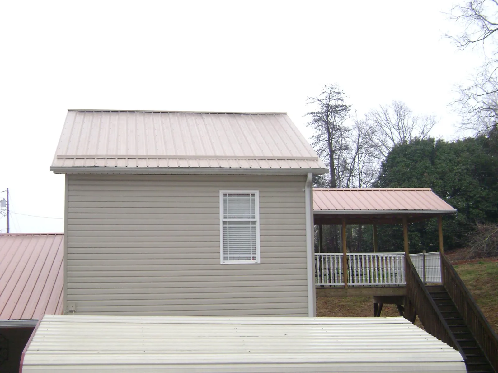 Tan metal roofs on a two story addition and attached porch, from a Roof Replacement job in Fruitland Park